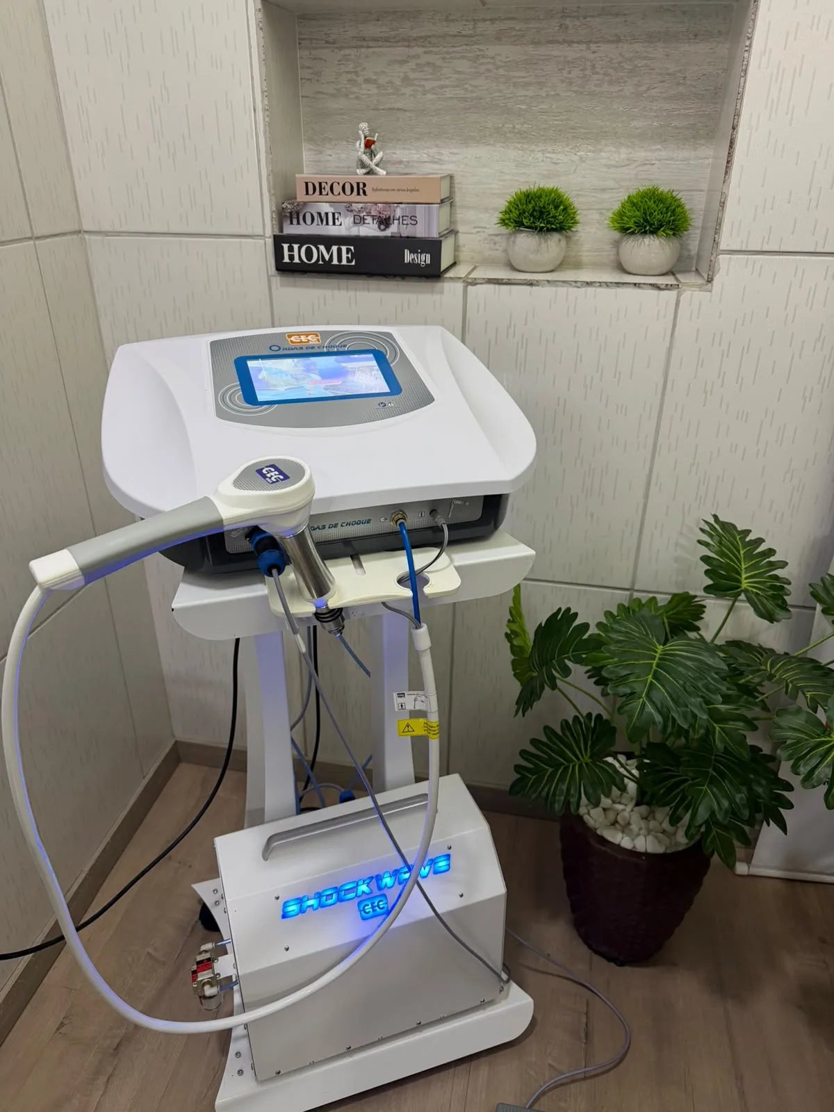 Equipamento de ondas de choque da SF Centro Terapêutico, sobre um carrinho em sala de atendimento.
